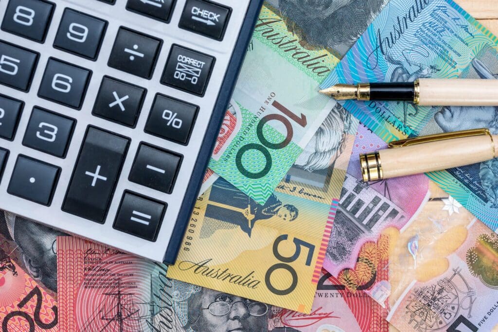 A calculator and pen with Australian cash on a table - represents using bid metrics to calculate tendering investments.